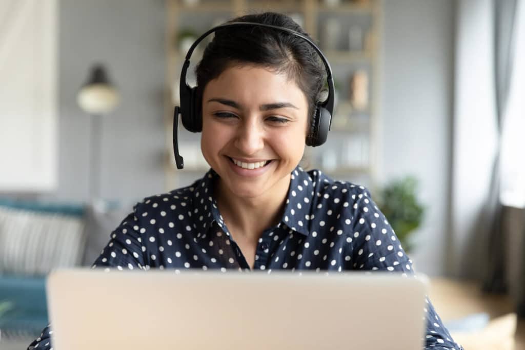 Lächelnde Kollegin mit Headset am Laptop