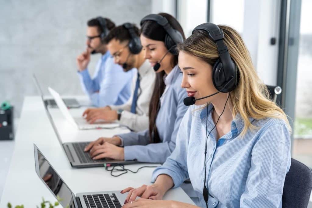 Mehrere Mitarbeiter sitzen mit Headset am Computer